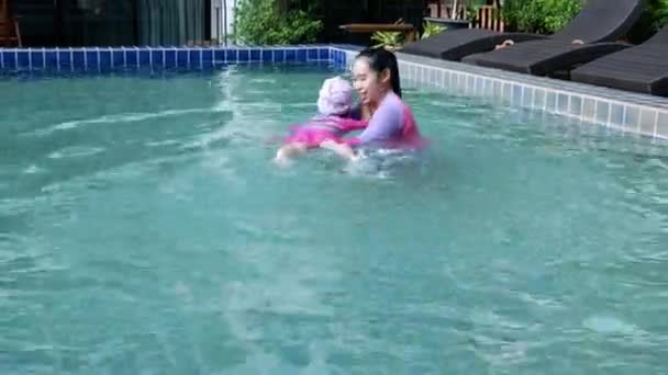 Asian little child girl learning to swim lessons from mother take care in a pool on summer vacation day. - Video, Çekim