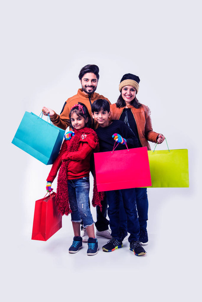 Famiglia indiana con borse della spesa in inverno vestiti caldi sullo sfondo bianco - Foto, immagini