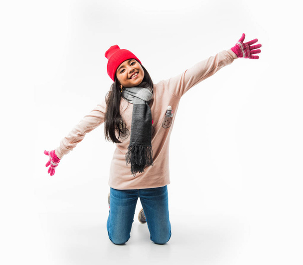 Porträt eines süßen indischen Mädchens in Winterkleidung, das vor weißem Hintergrund posiert - Foto, Bild