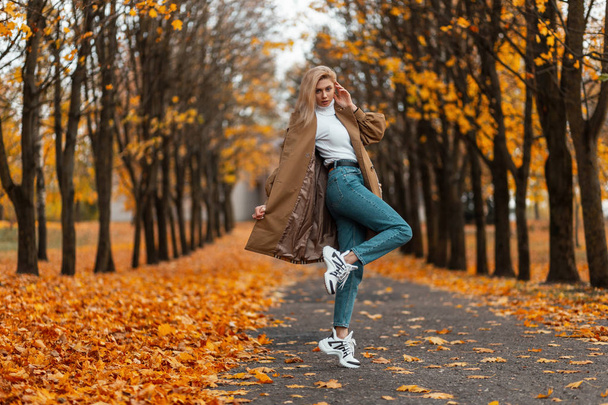 Modell elegáns fiatal nő elegáns ruhákat divatos cipő a parkban egy meleg őszi napon. Divatos városi szőke lány élvezi a sétát az erdőben. Őszi fiatal női divat. Alkalmi stílus. - Fotó, kép