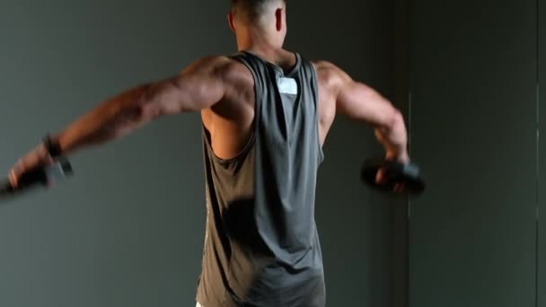Молодий атлетичний чоловік займається фізичними вправами у спортзалі. Плечі піднімаються з тарілками
 - Кадри, відео
