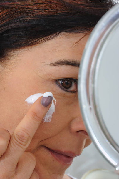 mature woman puts cream on face - Photo, Image