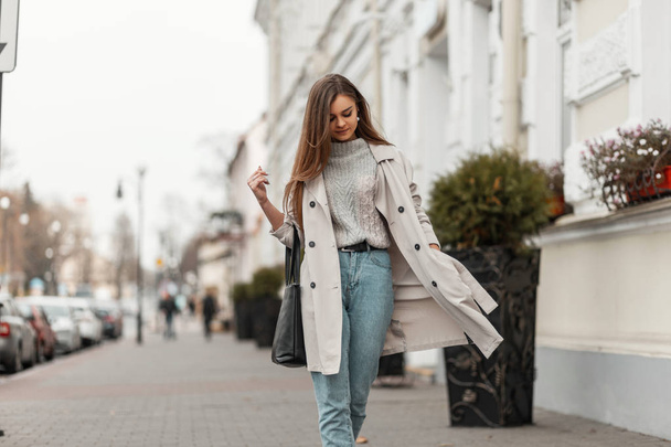 Tyylikäs malli nuoren naisen muodikas vuodenaikojen vaatteita laukku kävelee ympäri kaupunkia lähellä vintage rakennuksen lämpimänä syyspäivänä. Kaunis tyttö trendikäs päällysvaatteet ulkona
.  - Valokuva, kuva