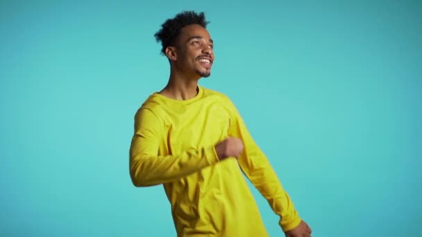 Young african american man smiling and dancing challenge dance in good mood on blue background.Unstoppable fun, happiness, comical portrait of guy isolated. - Séquence, vidéo