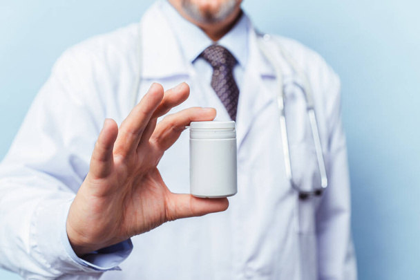 médecin tenant bouteille de pilules sur fond blanc. Le concept de médecine, pharmacologie, soins de santé
 - Photo, image
