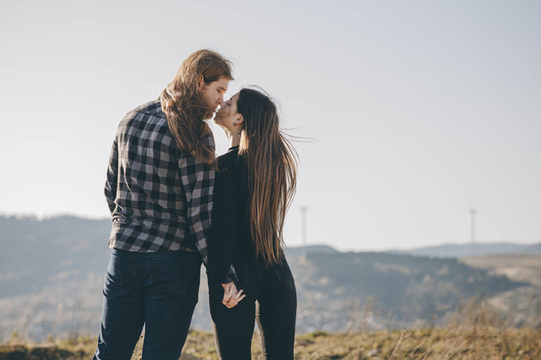 Love and valentines concept. Teenager lovers couple over natural background at the mountain and holding hands looking in the Sun rise. Black shadow loving people hug and kiss. - Foto, Imagem