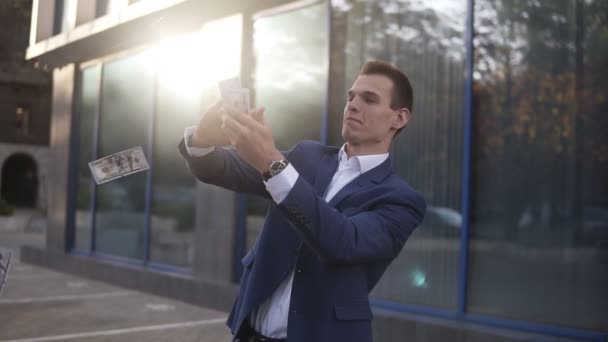 Rich caucasian businessman throw handful of banknotes in the air. Excited businessmen throw cash in front of office building and celebrate successful project and great deal - Felvétel, videó
