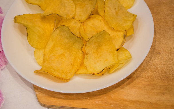Deliciosas papas fritas forma redonda, en un plato blanco en el fondo de una mesa de madera ligera, vista superior
 - Foto, imagen