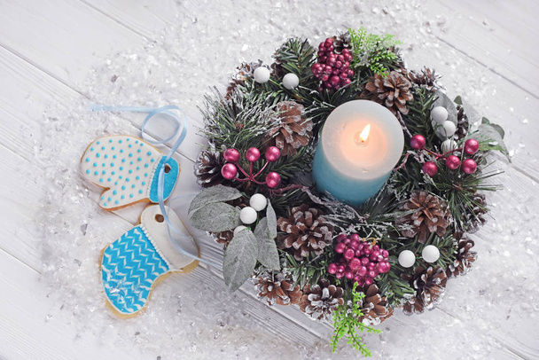 Christmas decorations for Christmas, wreaths and a candle and homemade gingerbread on a light background. The atmosphere of the holiday, Christmas mood. - Фото, зображення