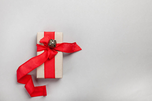boîte cadeau allongée avec un ruban rouge sur un fond gris - Photo, image