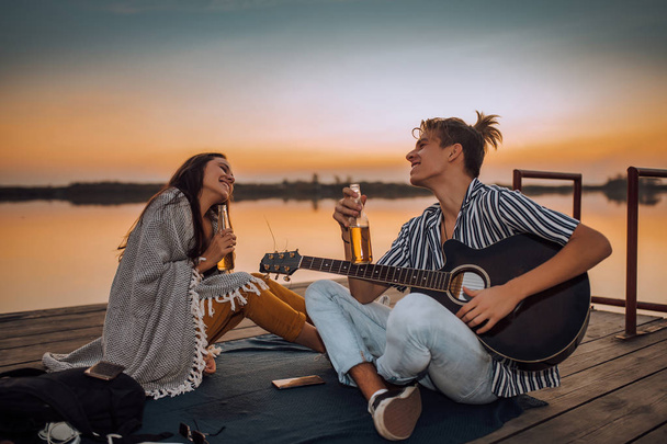 Young couple drinking beer and enjoying, while guy playing a gui - Photo, Image