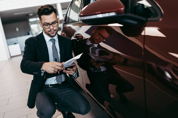 Car seller working in showroom and quality control checking of car details for the last time before buyer comes. - Φωτογραφία, εικόνα