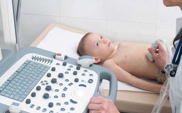 Doktor çocuğun karın boşluğunun ultrasonunu yapar. - Fotoğraf, Görsel