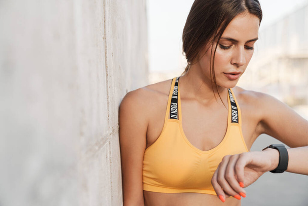 Image of woman in sportswear looking at smartwatch while walking - Fotoğraf, Görsel