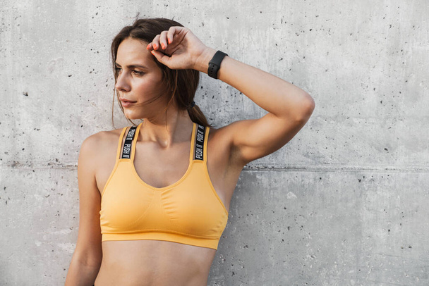 Image of woman in sportswear standing over concrete wall outdoor - Photo, Image