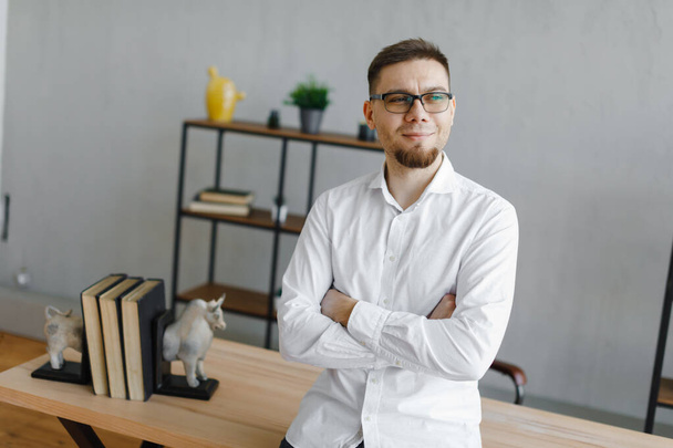 Handsome businessman in eyeglasses smiling while working in office - Foto, imagen