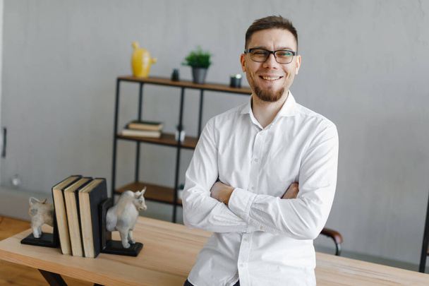 Красивий бізнесмен в окулярах посміхається під час роботи в офісі
 - Фото, зображення