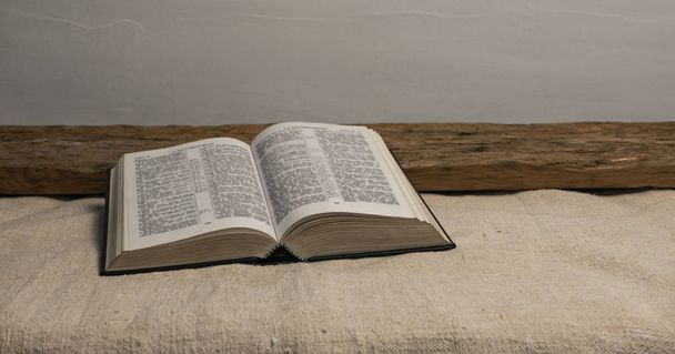 Avaa Pyhä Raamattu vanhalla puupöydällä ja valkoisella seinällä. Uskonnon käsite
. - Valokuva, kuva
