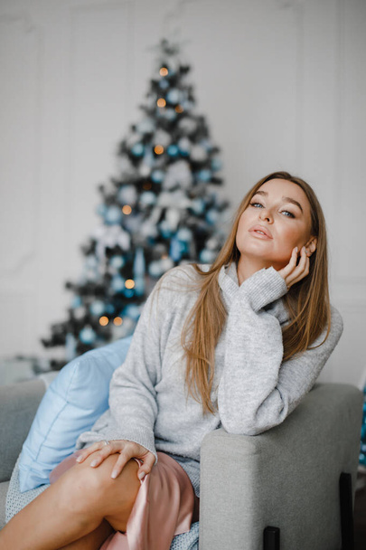 Feiertage, Feiern und Menschen-Konzept - junge Frau in elegantem Pullover vor weihnachtlichem Hintergrund - Foto, Bild