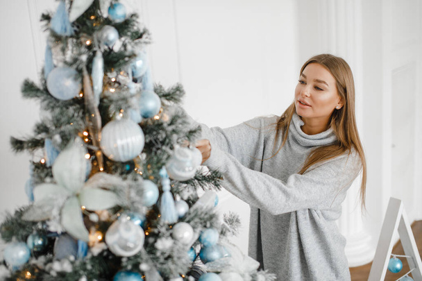 a girl in a sweater decorates a Christmas tree. New Year concept. - Foto, Bild
