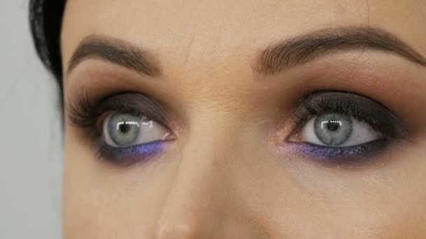 Mooie dure stijlvolle avond make-up rokerige ogen van ongewone grijze en blauwe schaduw van oogschaduw. Mooie vrouwelijke blauwe ogen van dichtbij bekijken - Video