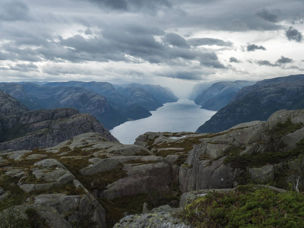 View on landscape with rock,blouders, stone and Lysefjord on hike to Preikestolen massive cliff famous Norway viewpoint Moody sky, autumn day. Nature and travel background, vacation and hiking holiday - Photo, Image