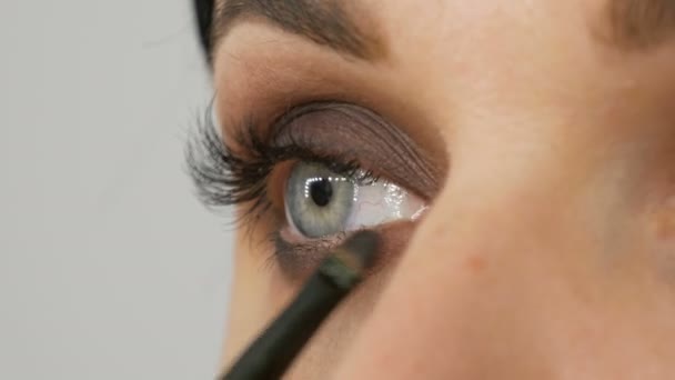 A special gray brush or pencil for eye makeup applies eye shadow on lower eyelid - Footage, Video