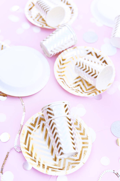 Праздничная композиция с бумажной посудой и конфетти на розовом фоне
. - Фото, изображение