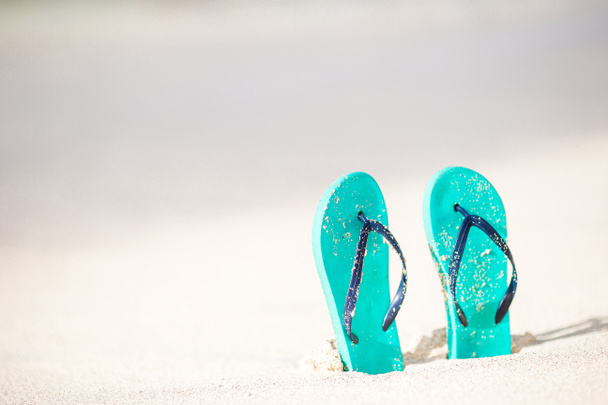 Летние мятные шлепанцы с солнцезащитными очками на белом пляже
 - Фото, изображение