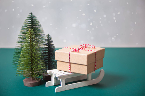 Christmas gift box on the sleigh with three small Christmas tree toys - Photo, Image