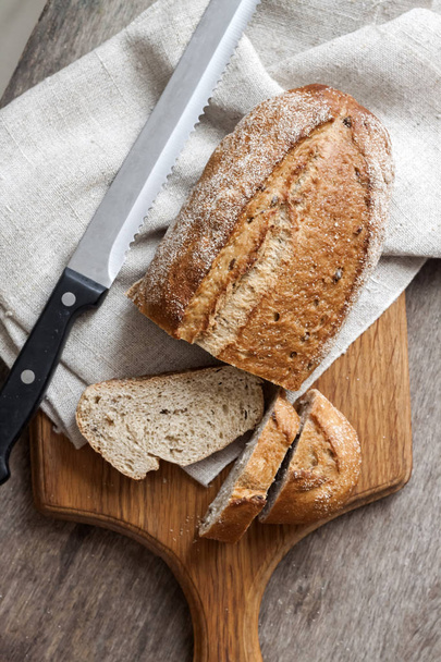 Chleb z całego chleba pszennego z plastrów na drewnianej płycie stołu kuchennego - Zdjęcie, obraz