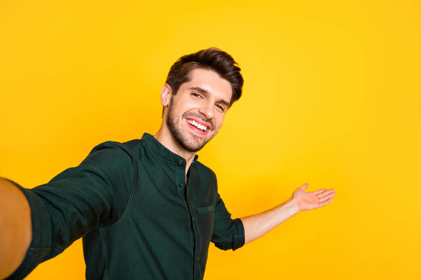 Close up photo of positive cheerful guy hold hand take selfie invite his blogging followers to perfect rest relax through video call wear casual style outfit isolated over yellow color background - Фото, зображення