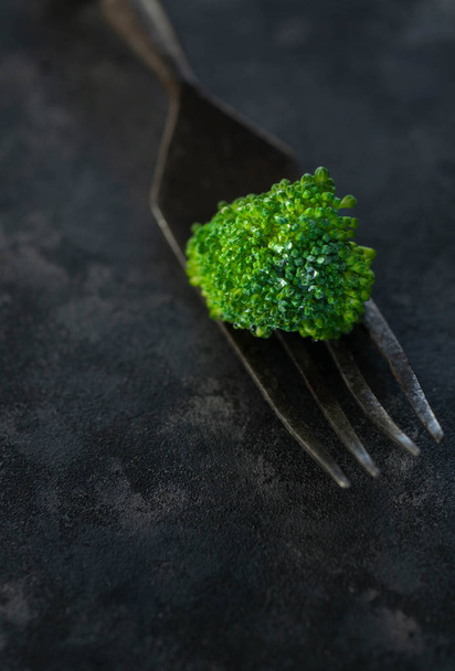 Close up broccoli with fork on black stone background - Fotó, kép