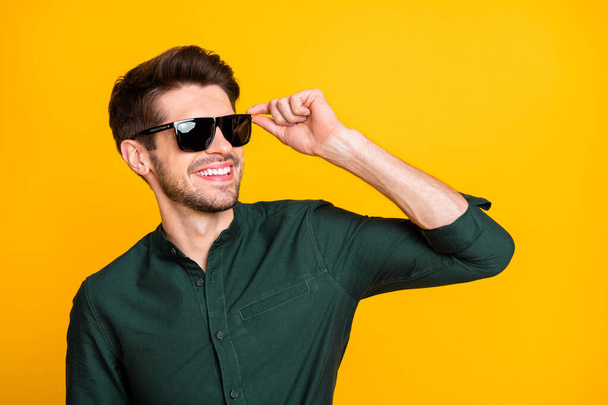 Photo of cheerful positive cool man in sunglass looking far away smiling toothily beaming holding eyeglasses spectacles isolated vivid color background - Photo, image