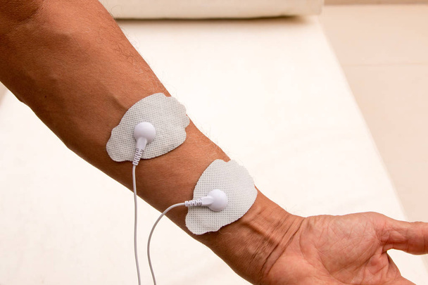Patient using a Home Electrical Nerve Stimulation Unit also Known as TENS Unit on his Body - Photo, Image