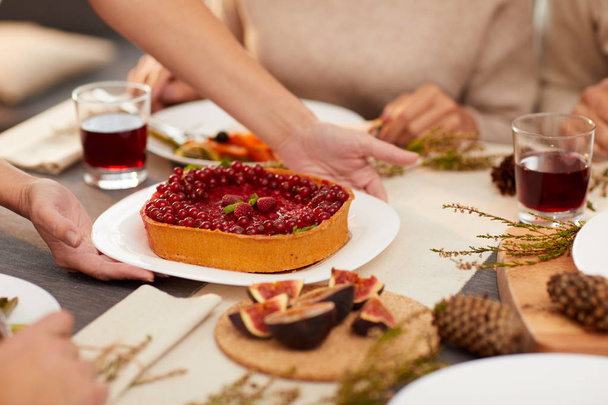 Крупним планом жінка, що подає солодкий ягідний пиріг з кухонним ножем на столі і гостями
 - Фото, зображення