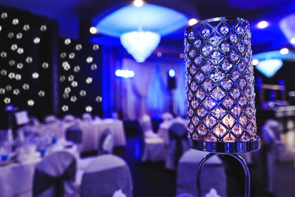 Candle light dinner in purple events room. Crystal glass lights indoor of party hall. Beautiful violet decoration in modern banquet restaurant. Holiday table setting. Romantic background for event celebration.  - Photo, Image