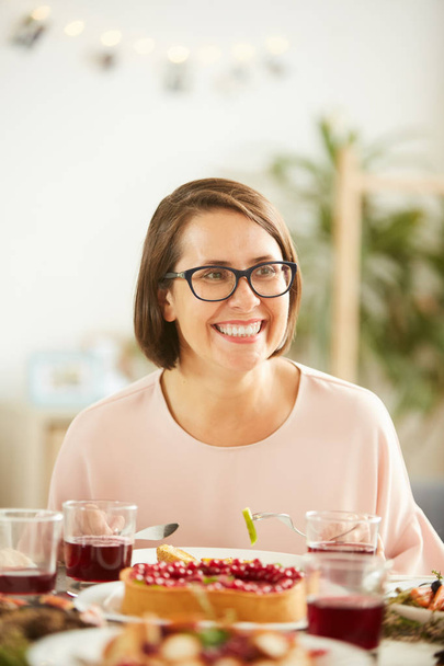 Happy young woman in eyeglasses sitting at the table and laughing while have dinner - Fotografie, Obrázek