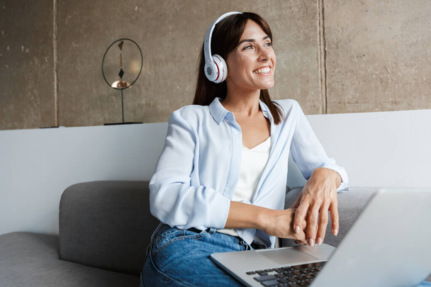 Woman indoors at home listening music with headphones - Foto, Bild