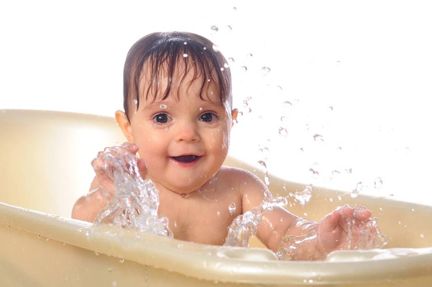 Happy baby girl under splashes of water in bath - Zdjęcie, obraz