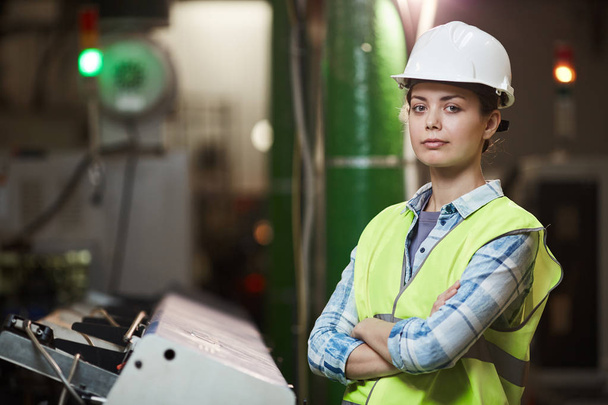 Portrait of female foreman in protective workwear standing with arms crossed and looking at camera while working in the plant - Fotografie, Obrázek