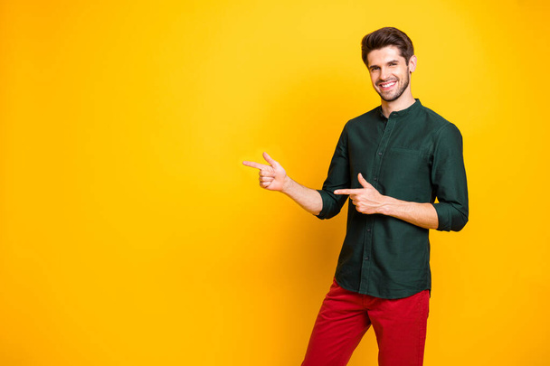 Photo of cheerful positive fun guy pointing at empty space with forefingers demonstrating place to be fulfilled smiling toothily isolated vivid color background - Fotografie, Obrázek