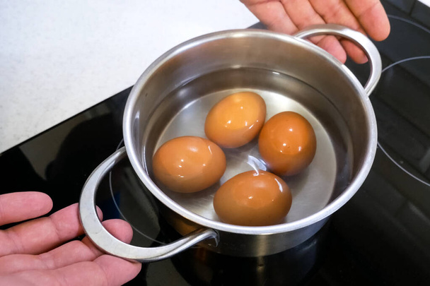 Βραστά αυγά στο τηγάνι αφαιρούνται από τη σόμπα. - Φωτογραφία, εικόνα