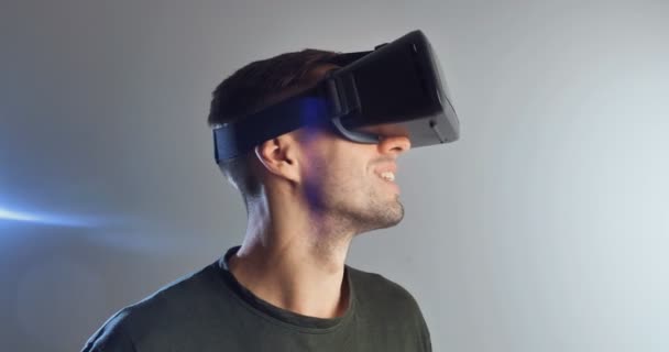 Young man wearing virtual reality technology VR Glasses. Man surprised by augmented reality in virtual reality helmet on a white background - Záběry, video