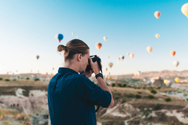 Young man photographer making pictures of air balloons at sunrise time in Cappadocia - Foto, imagen