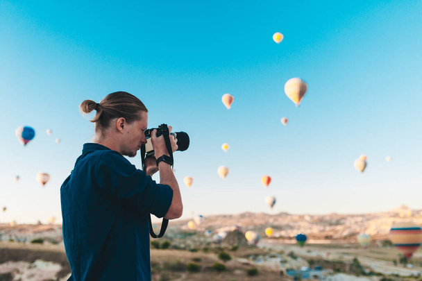 Young man photographer making pictures of air balloons at sunrise time in Cappadocia - Fotografie, Obrázek