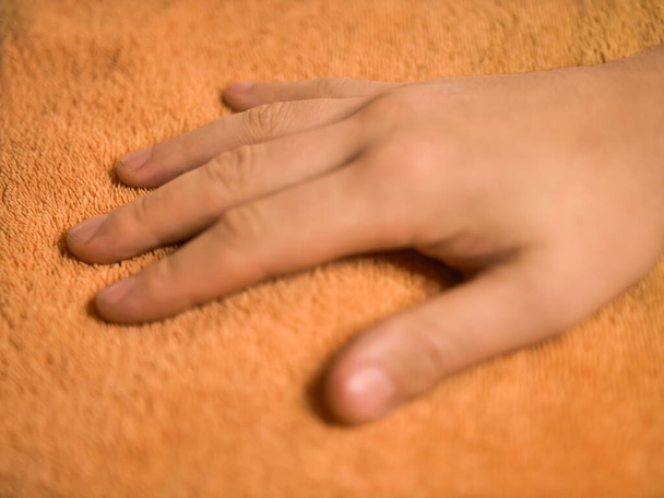 Mans hand touches a terry orange towel - Photo, Image