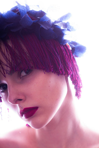hermosa joven con labios rojos, en su cabeza un borde de flores y flecos
 - Foto, Imagen