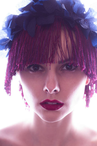 beautiful young girl with red lips, on her head a rim of flowers and fringe fringe - Foto, Imagen