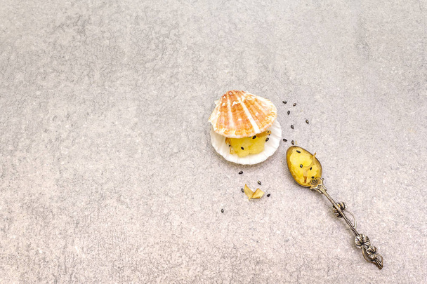 Капелинская икра в ракушках. Семена черного кунжута с хлопьями бонито. Легкая соленая икра закуска в серебряной ложке на каменном фоне, вид сверху
 - Фото, изображение